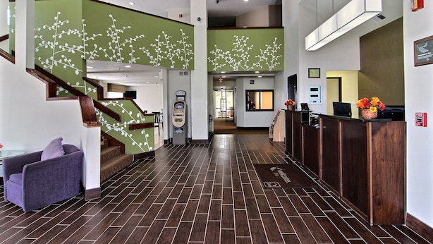 A hotel lobby with a staircase, reception desk, and a fire alarm.