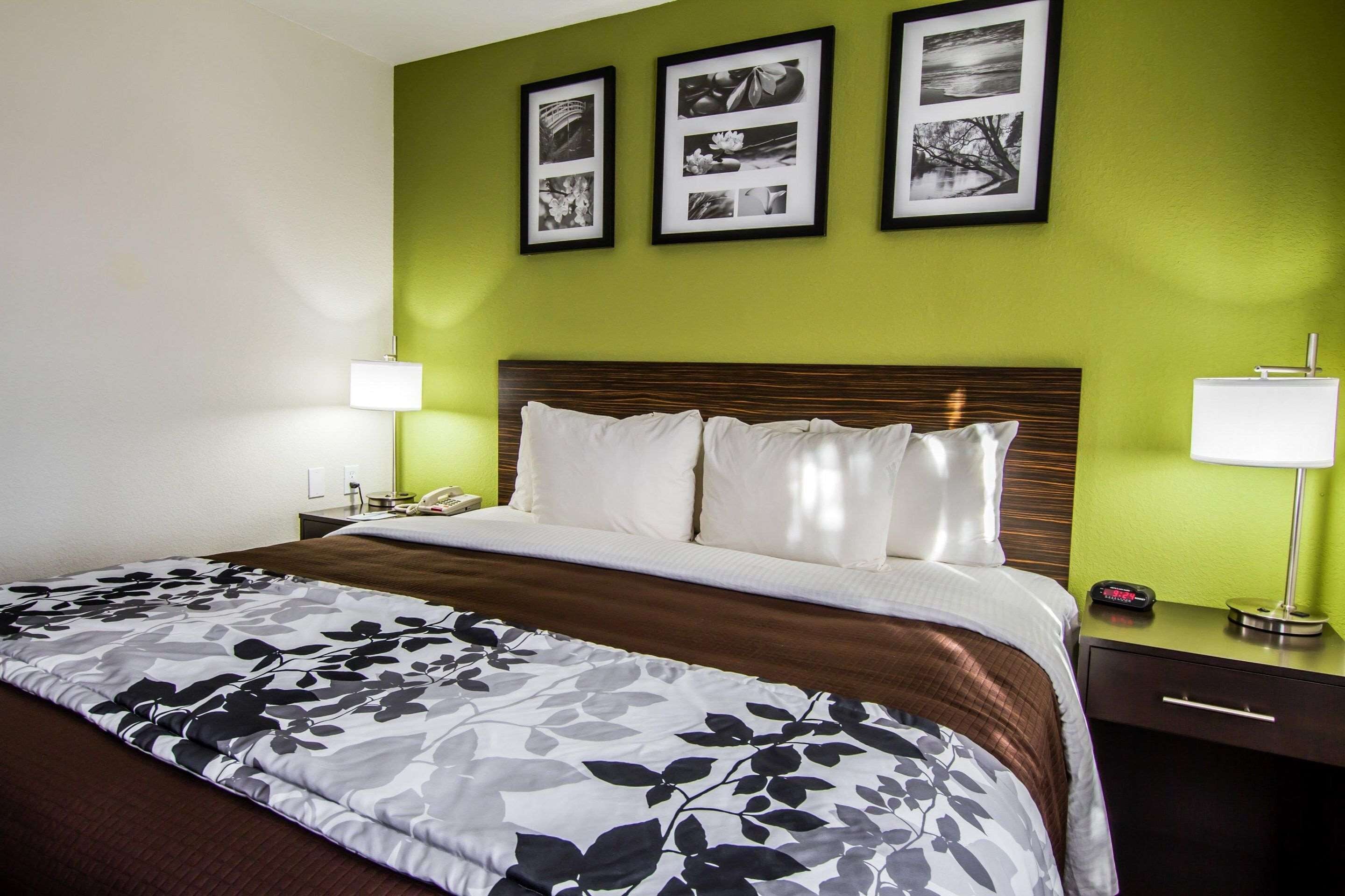 A hotel room with a large bed, green walls, and three framed pictures on the wall.