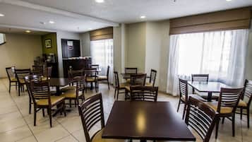 A dining area with multiple tables and chairs, a coffee machine, and a counter with a menu board.