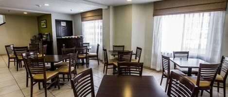 A dining area with multiple tables and chairs, a coffee machine, and a counter with a menu board.