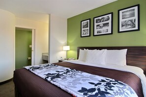 A hotel room with a large bed, a nightstand, a lamp, and three framed pictures on the wall.
