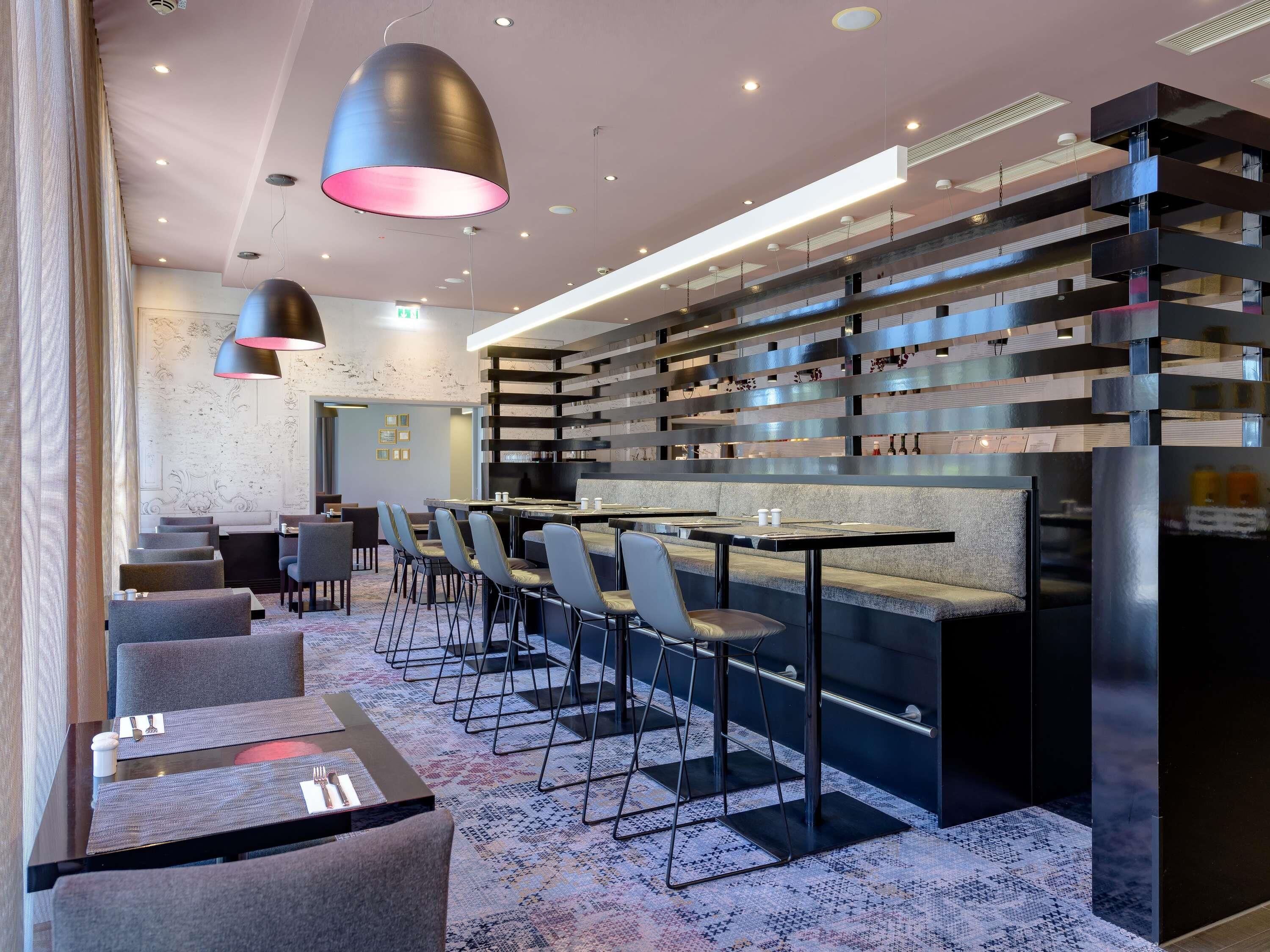 A modern hotel lobby with a bar area, seating, and a decorative wall.