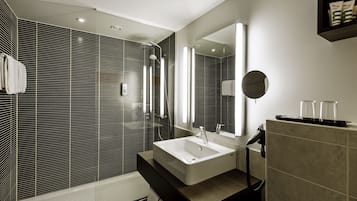 A modern bathroom with a large sink, mirror, and shower.