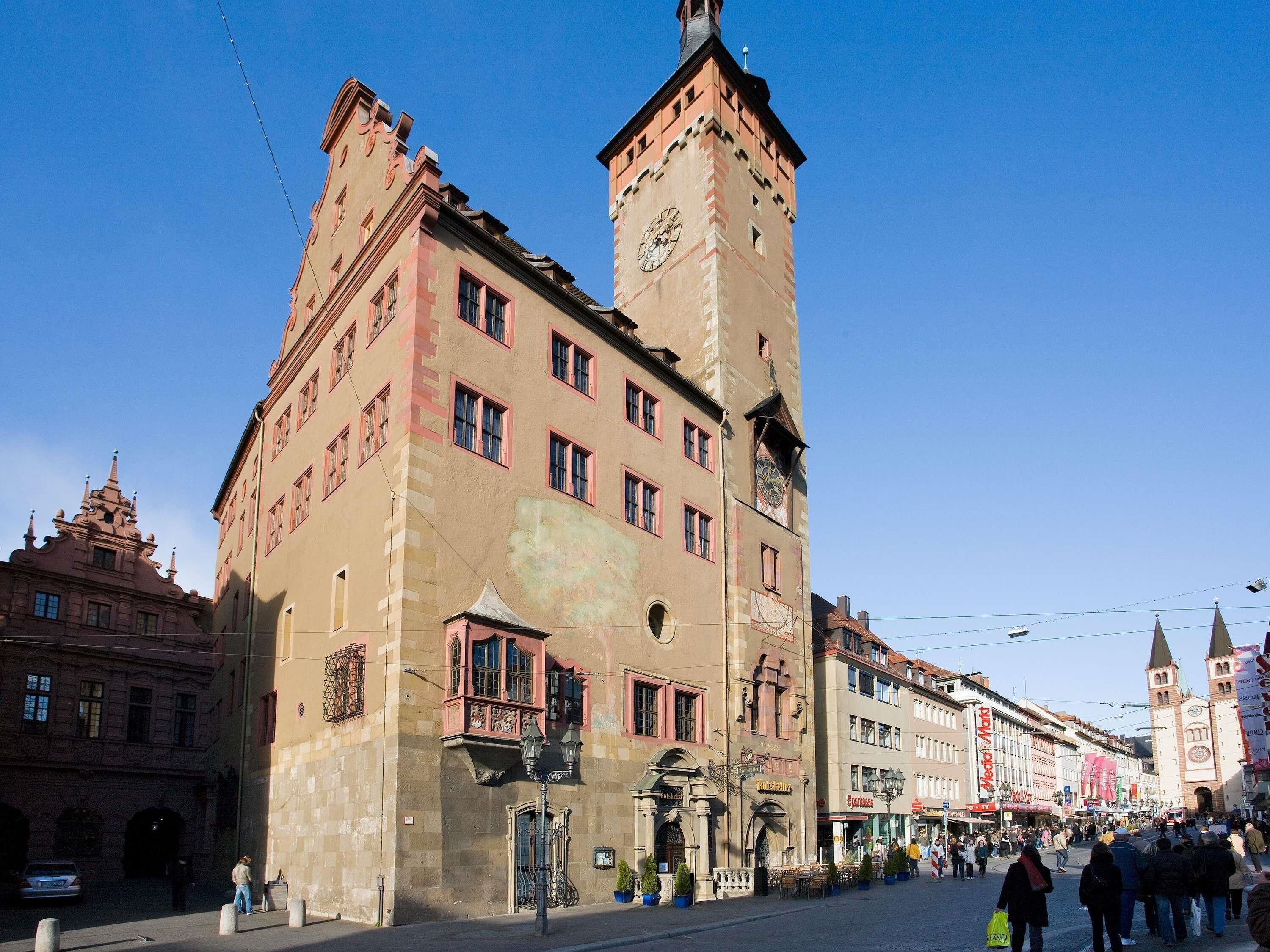 Ein historisches Gebäude mit einem markanten Glockenturm, großen Fenstern und einem zentralen Eingang.