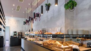A modern breakfast bar with a variety of food items, a coffee machine, and hanging plants.