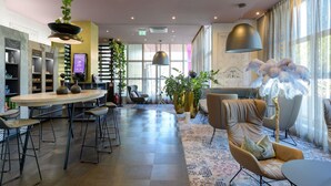 Um saguão de hotel moderno com área de bar, assentos e janelas amplas.