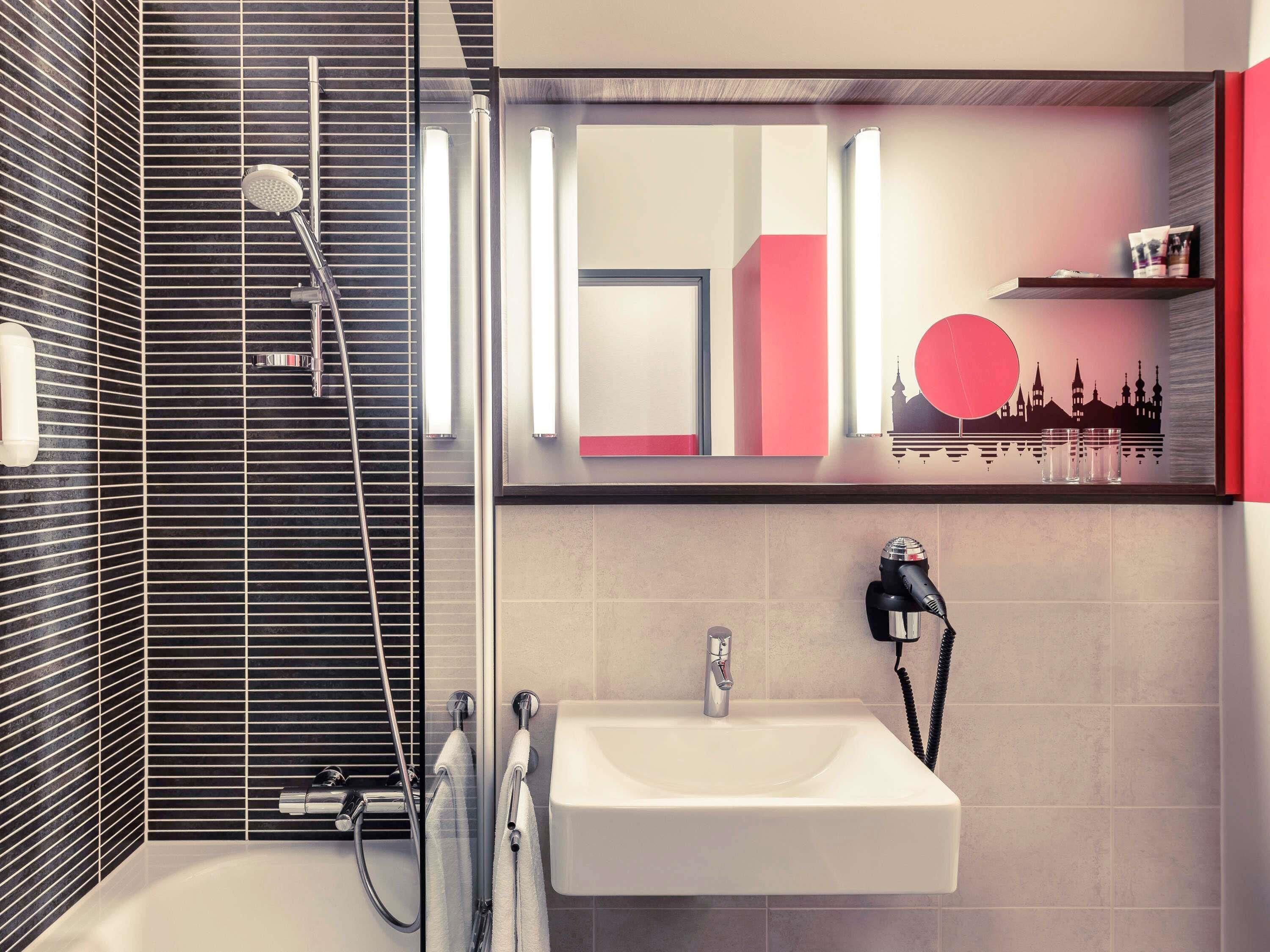 A modern bathroom with a shower, a sink, and a mirror.