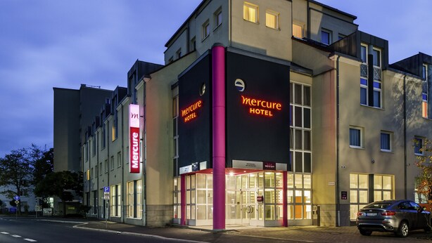 A modern hotel with a prominent entrance, large windows, and a visible parking area.