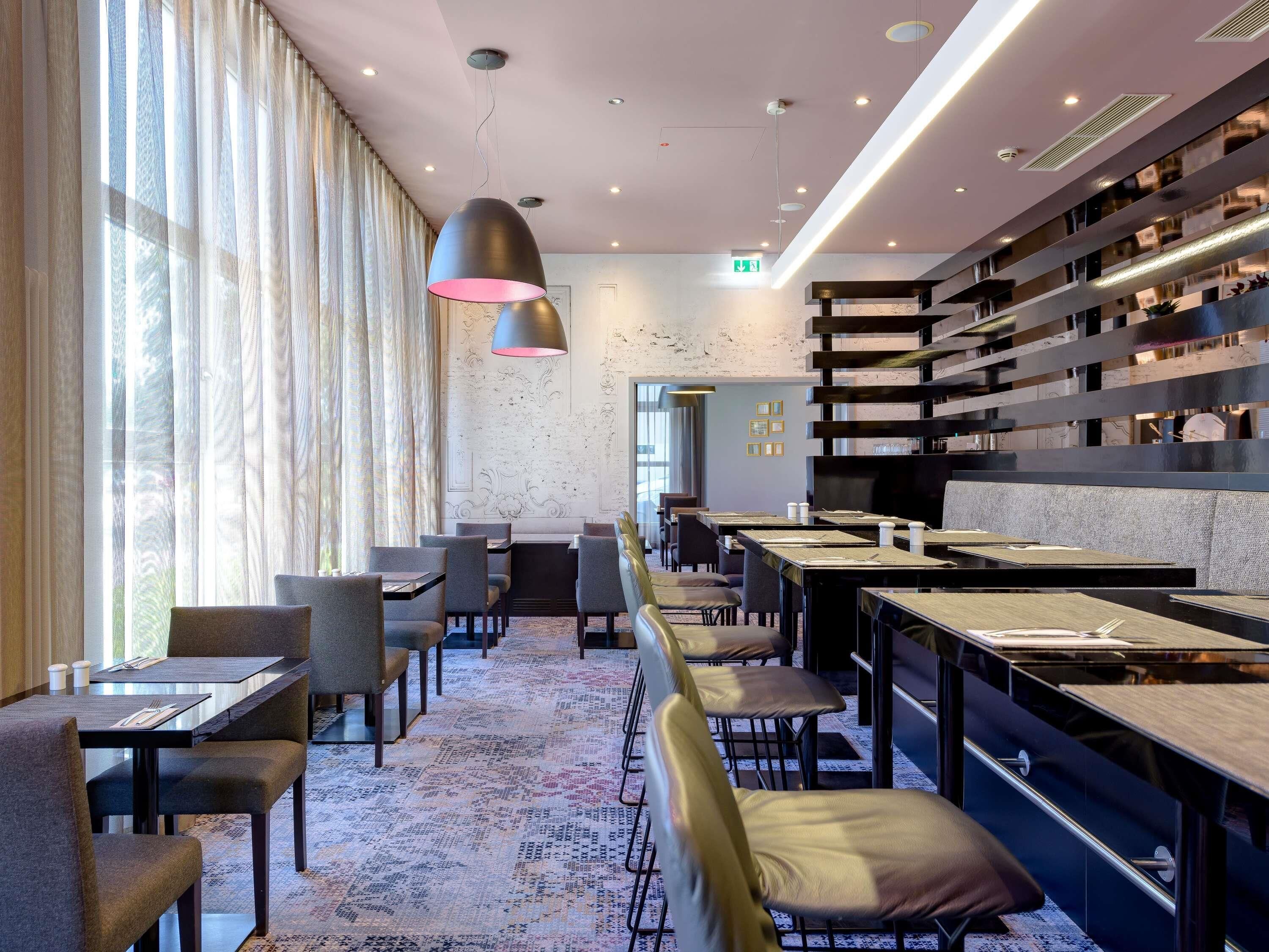 A modern restaurant with high tables, chairs, and a patterned floor.