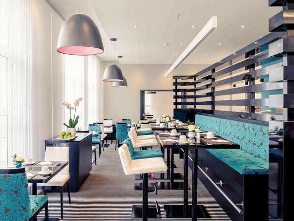 Un restaurante moderno con suelo a rayas, asientos negros y color turquesa, e iluminación colgante.
