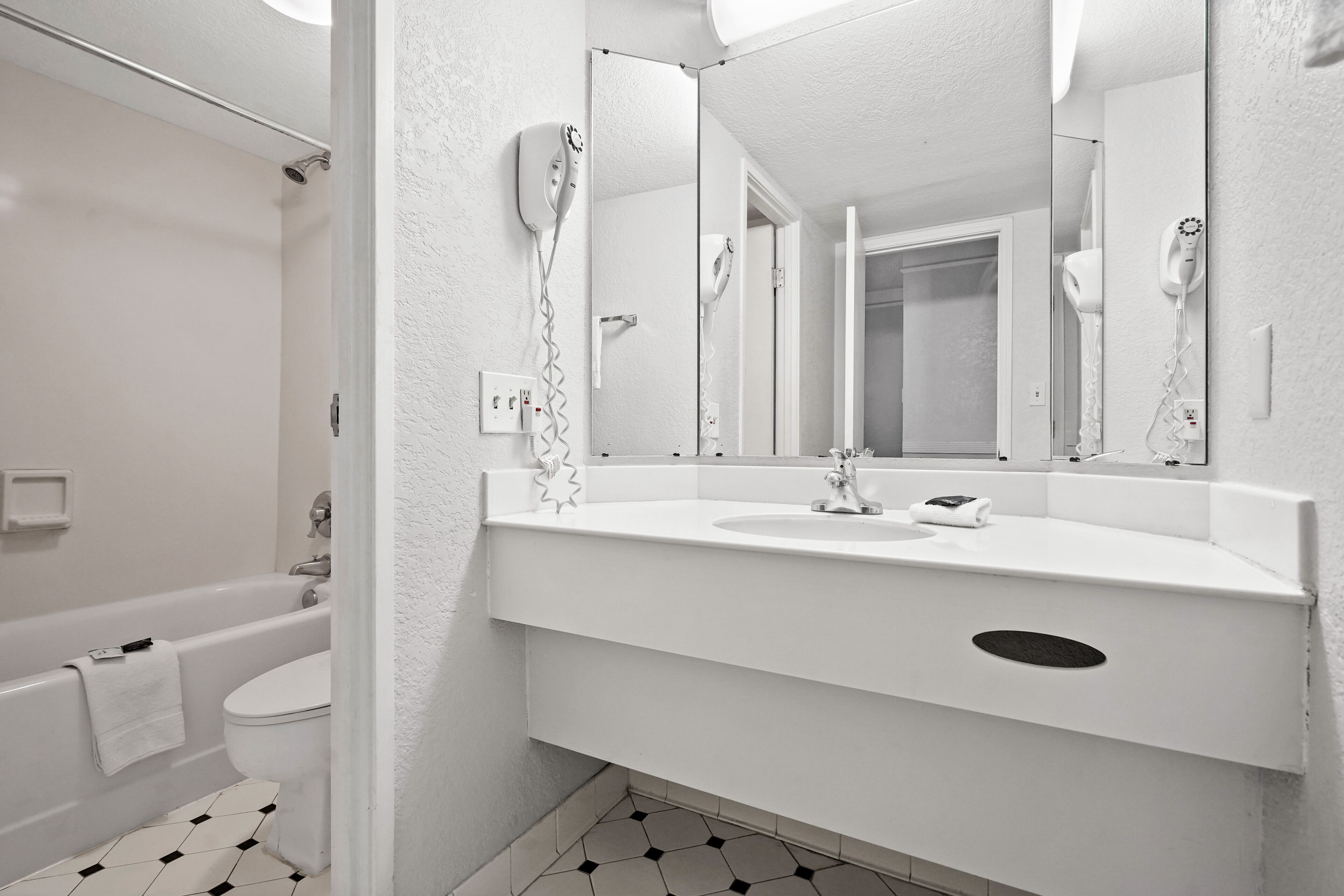 Un baño moderno con un lavabo blanco, espejo y zona de ducha.