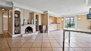 A spacious lobby with a fireplace, tiled flooring, and a large window offering a view of the outdoors. - La Quinta Inn by Wyndham Costa Mesa / Newport Beach (Costa Mesa)