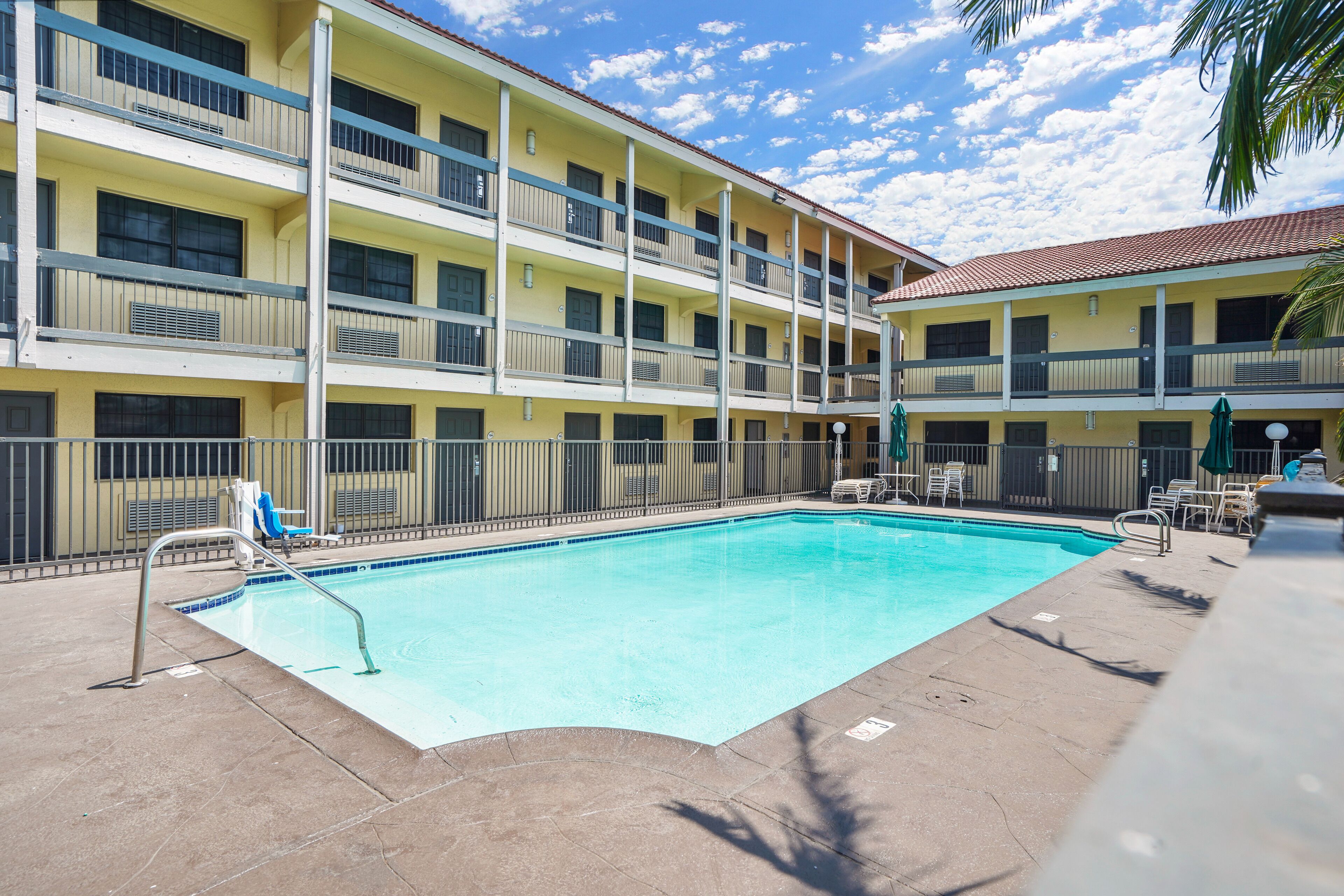 A hotel with a pool, multiple balconies, and outdoor seating.