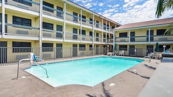 A hotel with a pool, multiple balconies, and outdoor seating.
