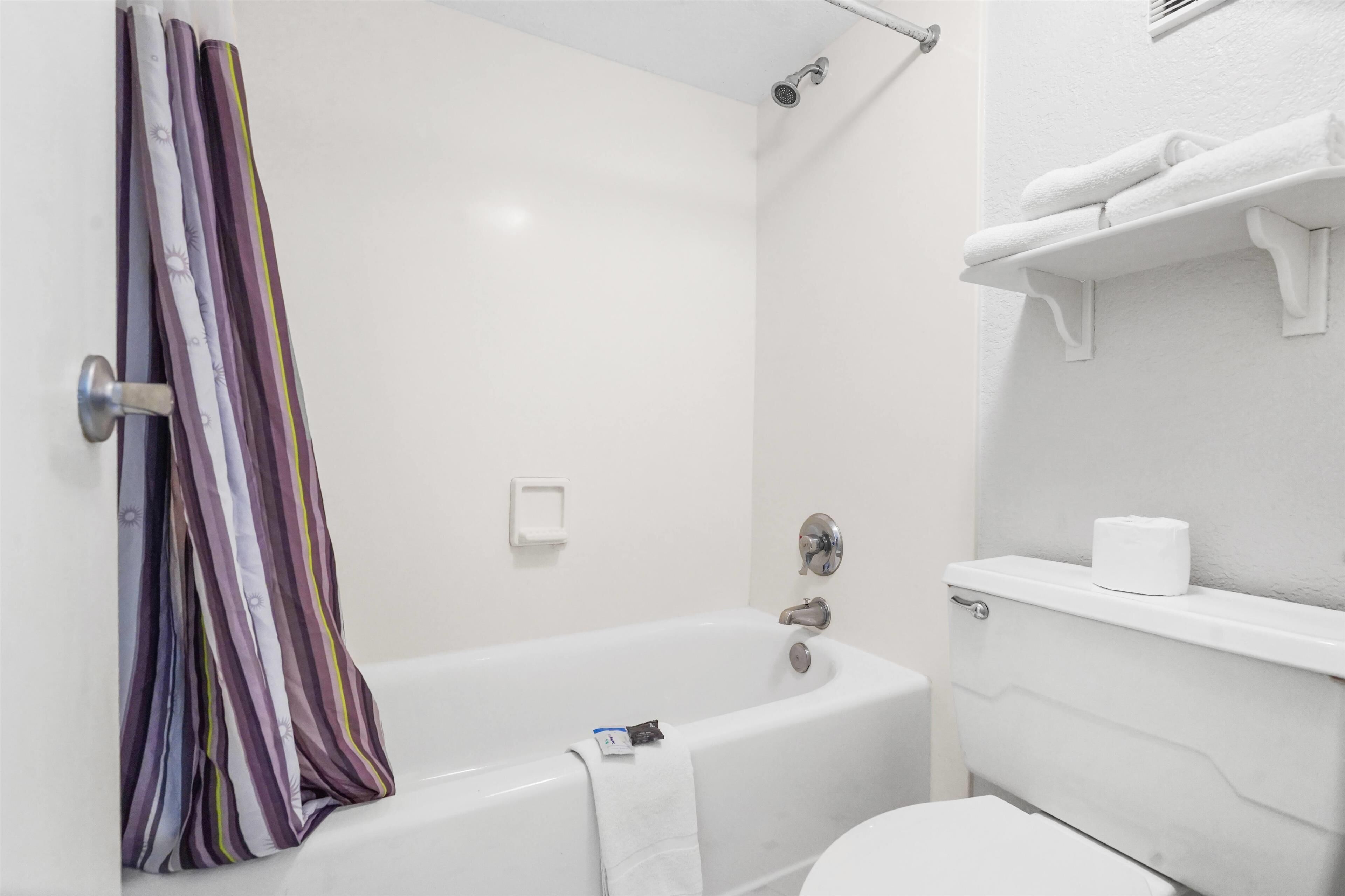 A bathroom with a bathtub, toilet, and towel rack.