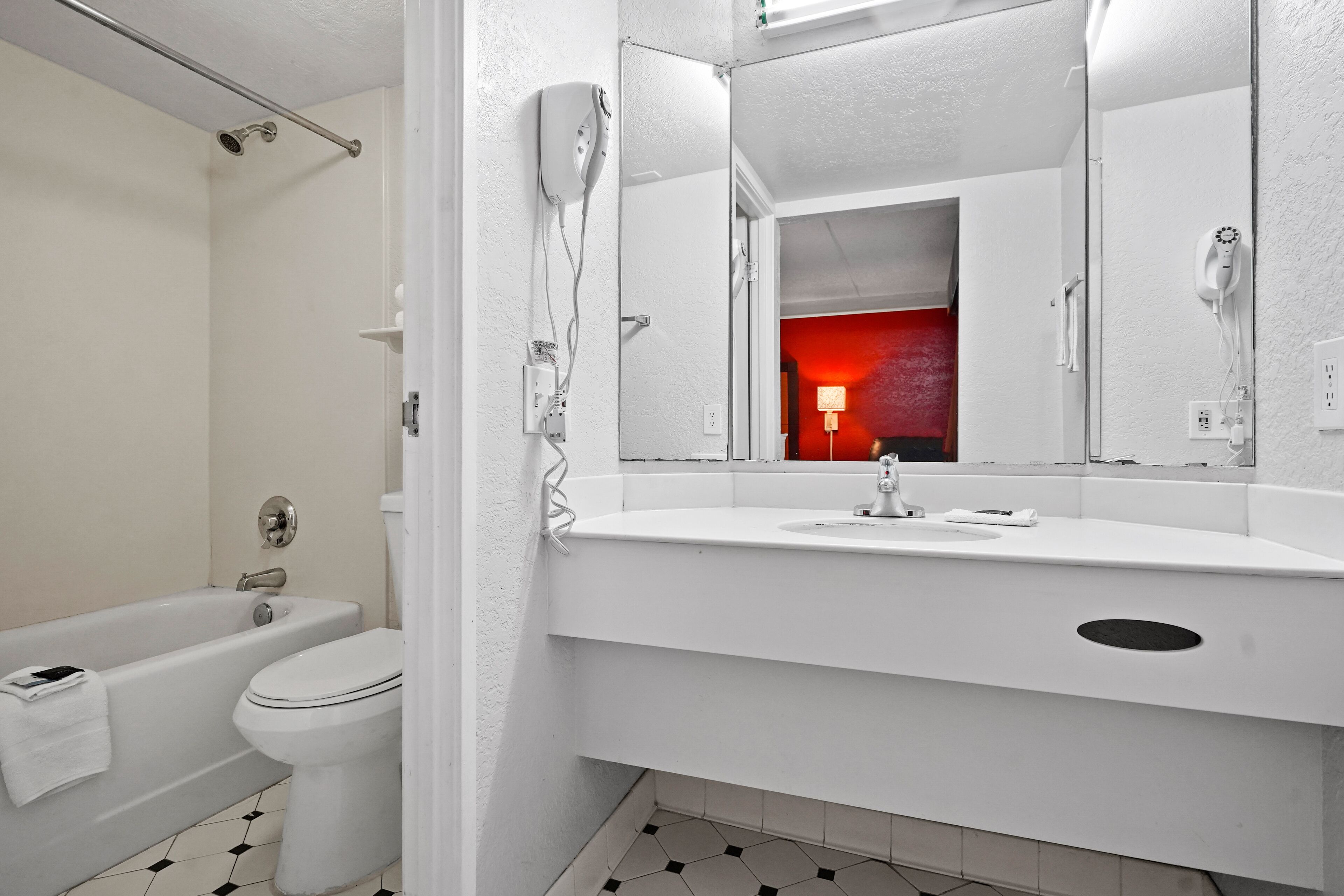 A modern bathroom with a bathtub, toilet, and a large mirror above the sink.
