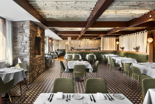 A restaurant with a stone fireplace, green upholstered chairs, and patterned flooring. - Hyatt Regency Lake Tahoe Resort, Spa and Casino (Incline Village)