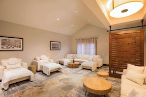 A spacious living room with a high ceiling, a stone floor, and a wooden partition. There are three sofas and two round tables. - Hyatt Regency Lake Tahoe Resort, Spa and Casino (Incline Village)