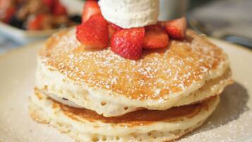 Una pila de tortitas con fresas y una bola de helado sobre un plato.