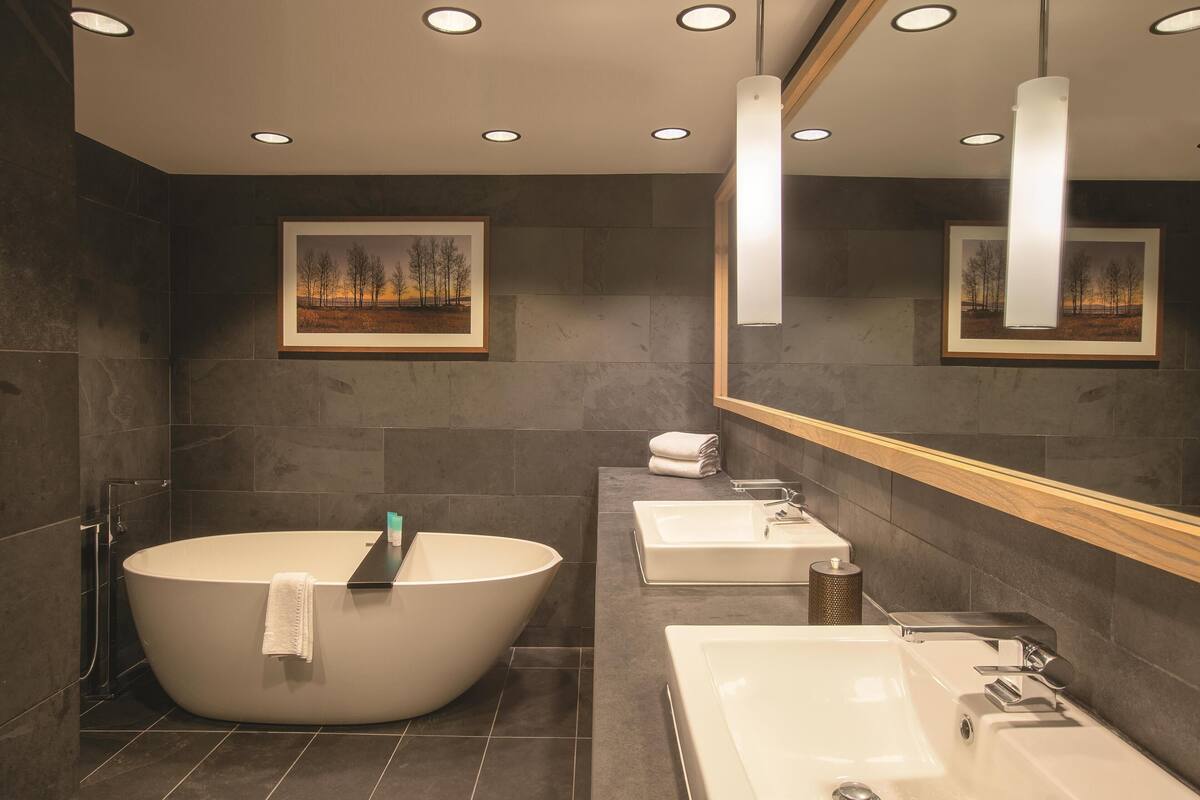 A modern bathroom with a freestanding bathtub, a vanity with a sink, and a large mirror.