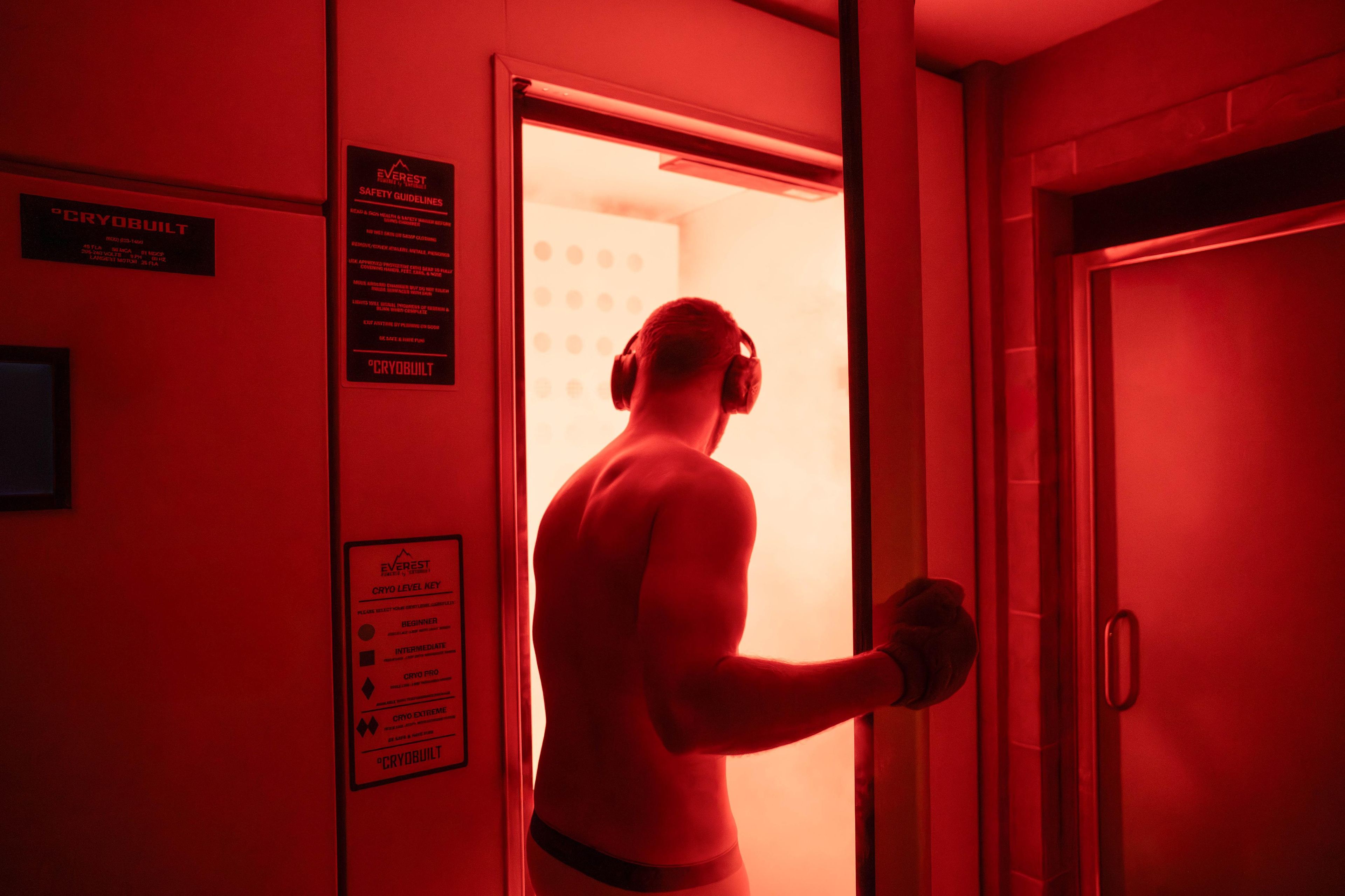 Eine Person in einem rot beleuchteten Raum mit Sicherheitshinweisen und einem Schlüssel für die Kryoebene an der Wand.
