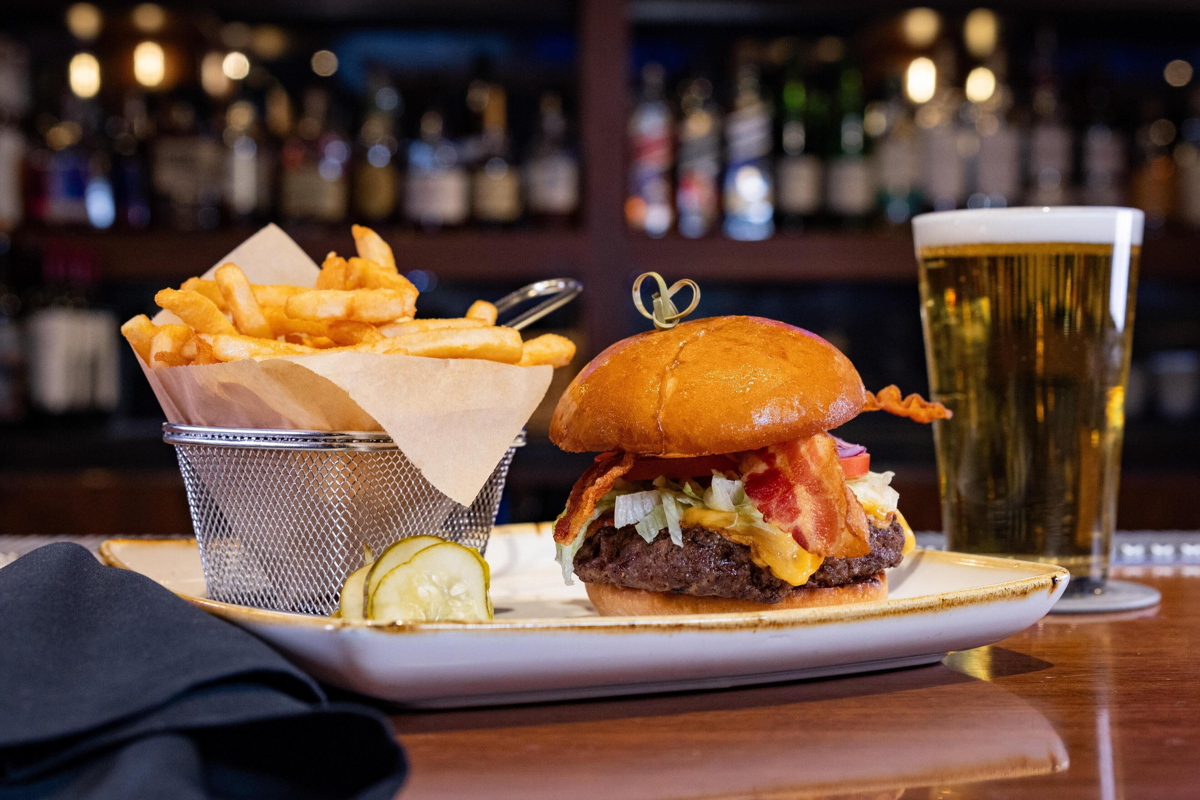 A burger with fries and a beer on a table.