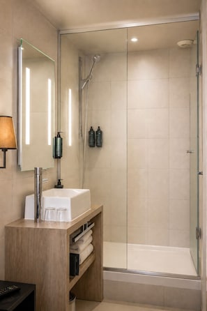 A modern bathroom with a glass-enclosed shower, a white sink, and a mirror. - Hotel Le Montmartre Saint Pierre (Paris)