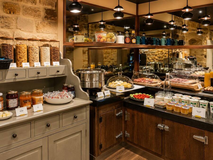 Un bufé de desayuno con diversos alimentos, frascos de condimentos y una pared de piedra de fondo.