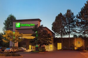 Un hôtel Holiday Inn avec une façade en briques, un parking bien visible et un ciel dégagé.