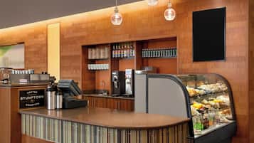 Una estación de café con un letrero de Stumptown Roasters, una máquina de café y una vitrina con pasteles.