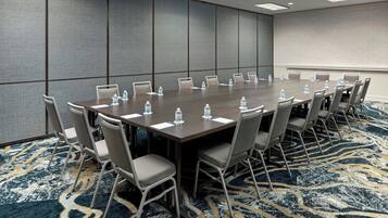 A conference room with a long table, chairs, water bottles, and a patterned carpet.