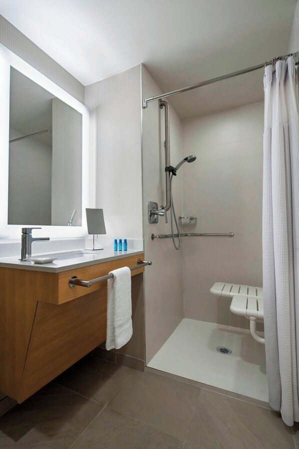 Un baño moderno con tocador, lavamanos, espejo, ducha e inodoro.