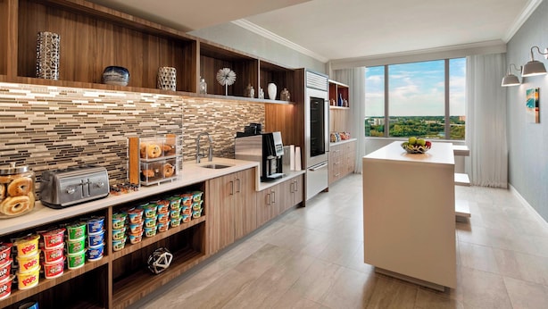 A modern kitchen with wooden cabinetry, a tiled backsplash, and a view of the city. - Delta Hotels by Marriott Richmond Downtown (Richmond)
