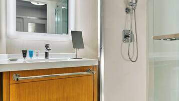 A modern bathroom with a glass-enclosed shower, a vanity with a mirror, and a towel rack.