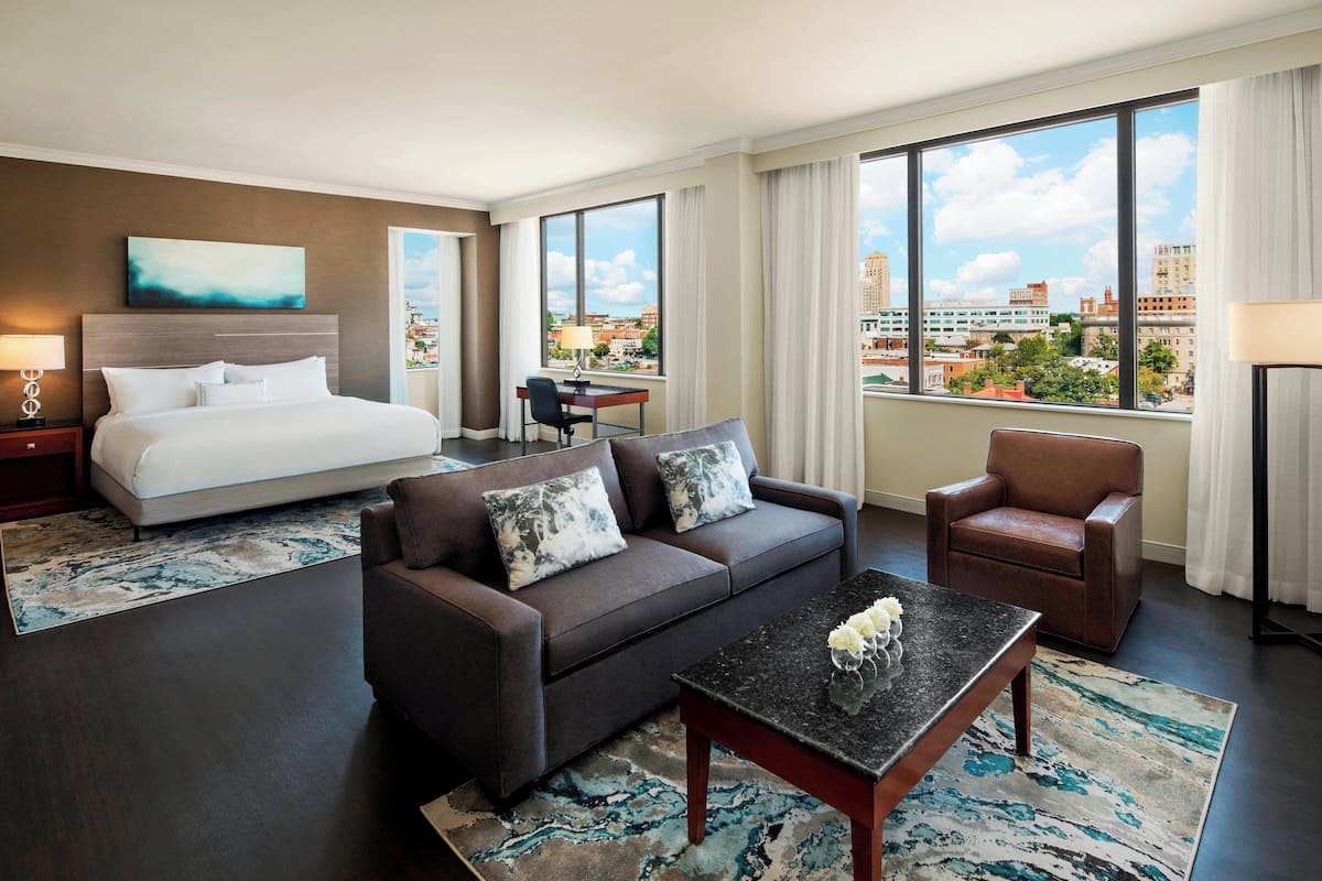 Ein Hotelzimmer mit Bett, Sofa, Couchtisch und Blick auf die Stadt.
