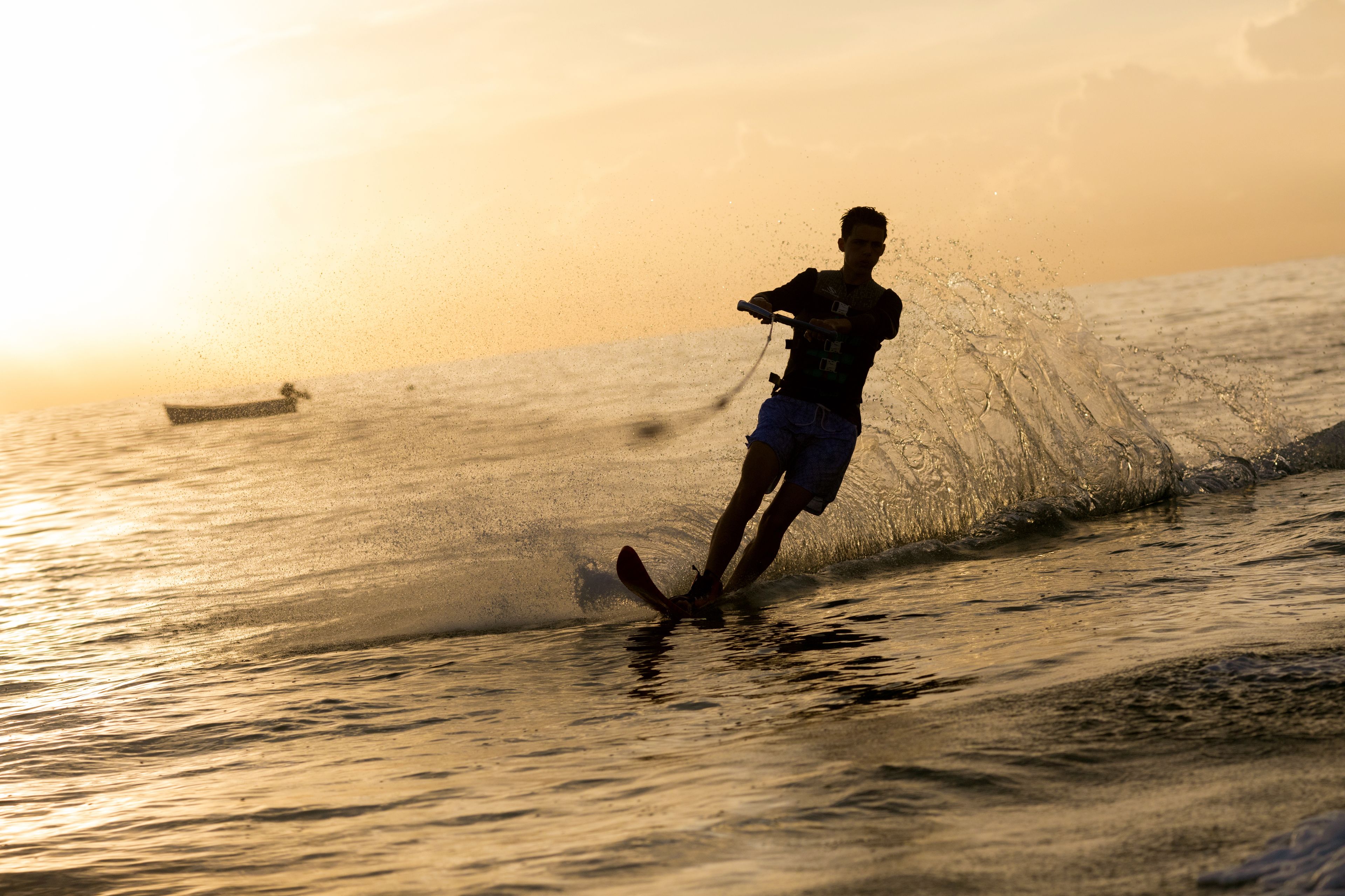 Uma pessoa praticando wakeboard em um corpo d'água ao pôr do sol.