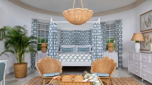 A room with a bed, two wicker chairs, a table with breakfast items, a potted plant, and a hanging basket. - Cobblers Cove - Barbados (Speightstown)