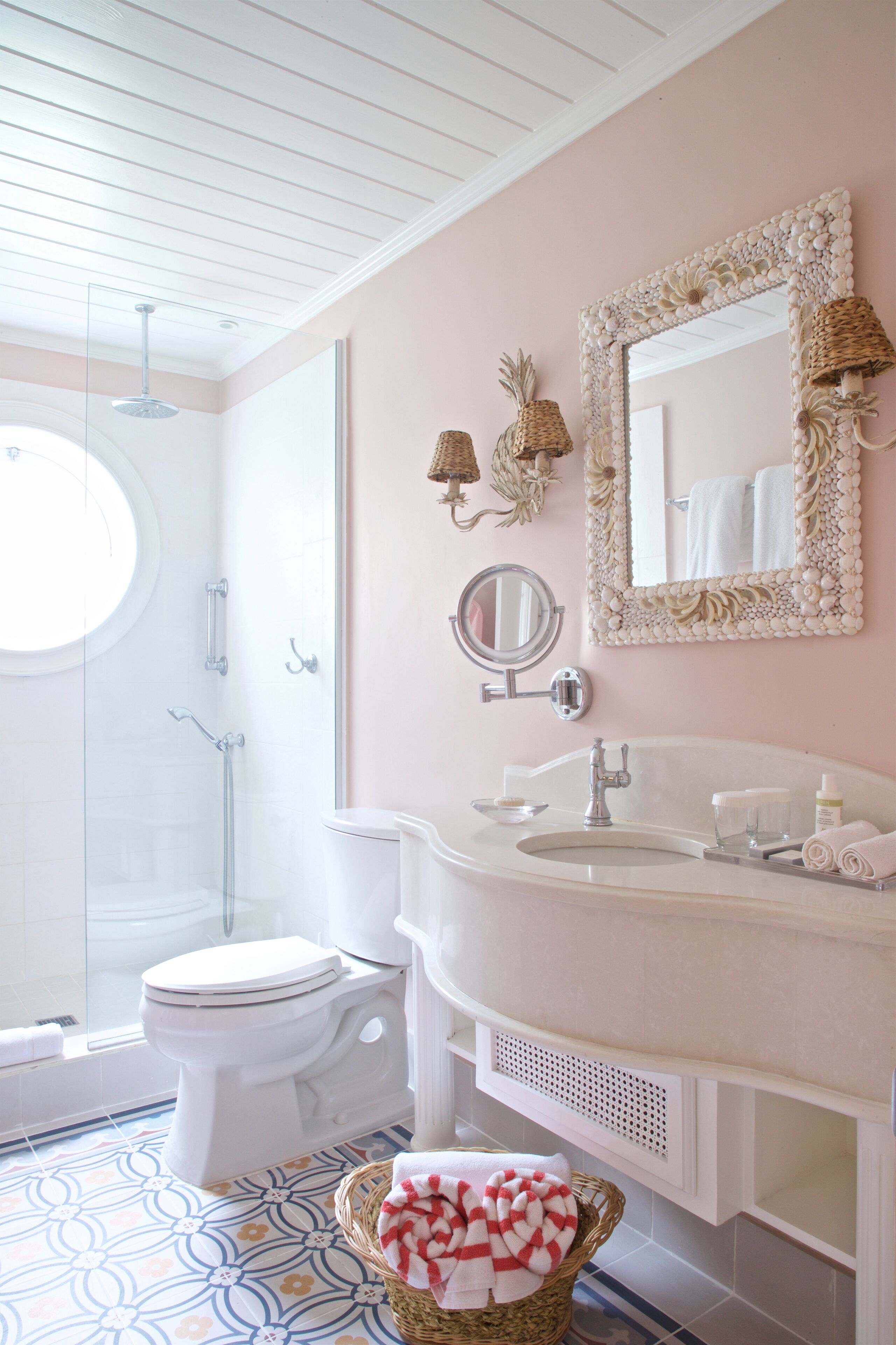 A bathroom with a shower, toilet, sink, and a mirror with decorative elements.