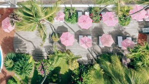 An aerial view of a beachside resort with a pool, palm trees, and beach umbrellas. - Cobblers Cove - Barbados (Speightstown)
