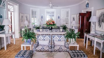 Amplia sala de estar con un sofá central, una mesa de centro y un comedor con mesa y sillas.