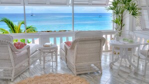A room with white wicker furniture, a view of the ocean, and a potted plant. - Cobblers Cove - Barbados (Speightstown)