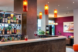 A bar area with shelves of liquor bottles, a wine glass, and hanging pendant lights.