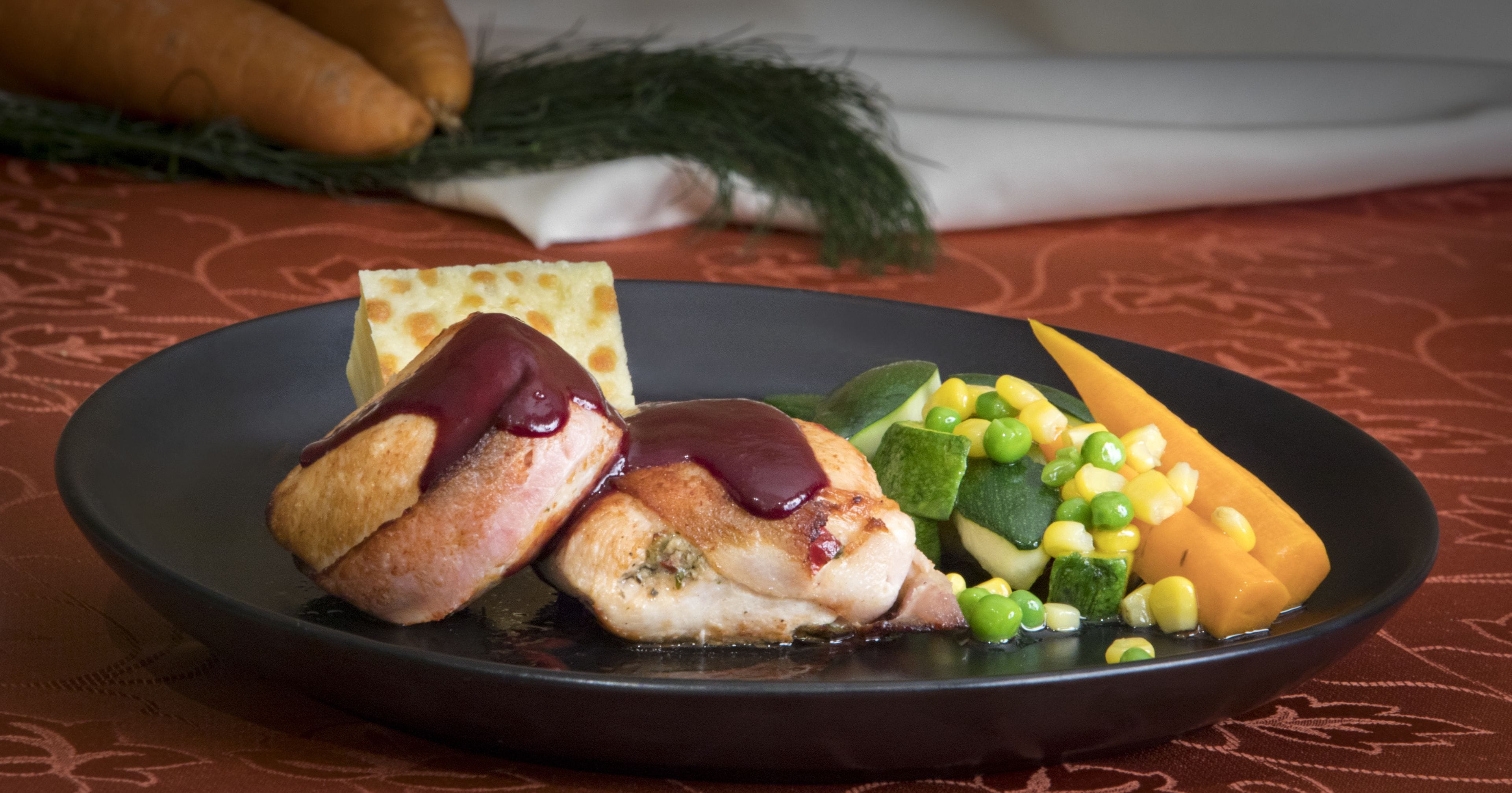 A plate with a piece of meat, a slice of bread, and mixed vegetables.