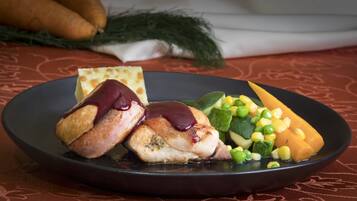 A plate with a piece of meat, a slice of bread, and mixed vegetables.