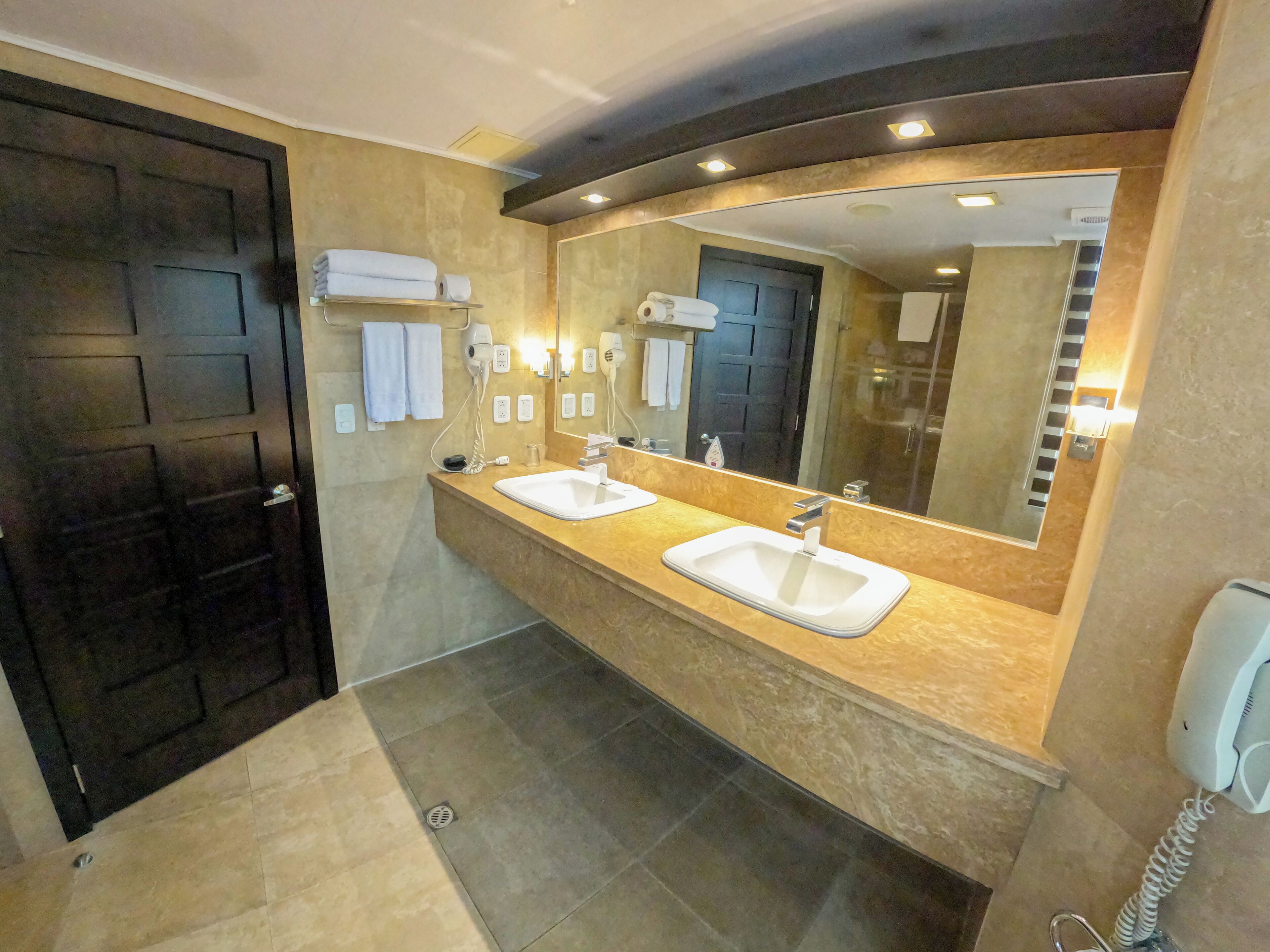 Casa de banho moderna com duas pias, um espelho grande e um secador de cabelo.