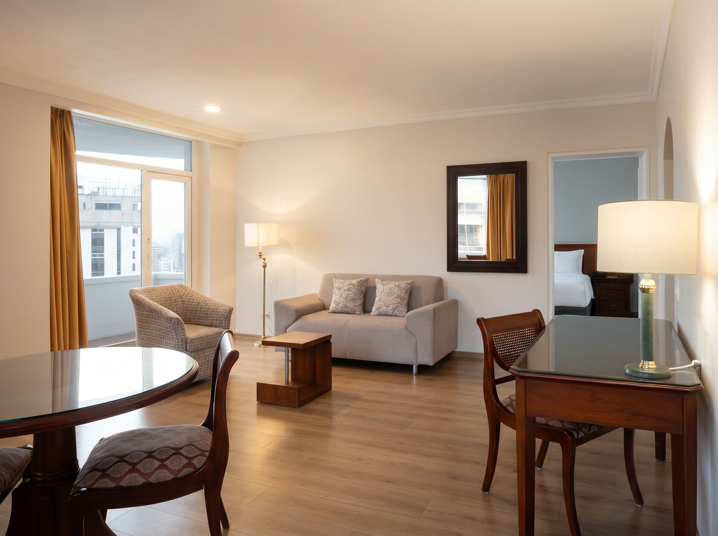 Habitación de hotel con una mesa de comedor redonda, dos sillones, un sofá, una lámpara de pie y un espejo en la pared.