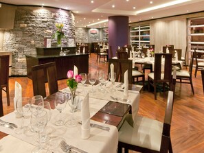 Un restaurant avec des tables dressées, un mur en pierre et une enseigne indiquant qu’il sert des sushis.