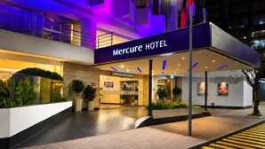 A hotel entrance with a sign reading 'Mercure HOTEL,' a reception desk, and a modern architectural design. - Mercure Alameda Quito (Quito)