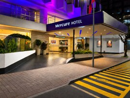 Entrada de un hotel con un cartel que dice 'Mercure HOTEL', un mostrador de recepción y un diseño arquitectónico moderno.