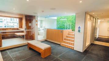 Relax in a stylish seating area with a cushioned bench and a unique green wall.